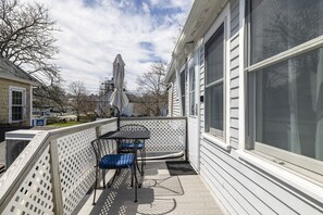 Une terrasse couverte avec une table et des chaises, une clôture blanche et une grande fenêtre.