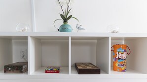 Una repisa con una planta pequeña, una figurita de pájaro, un juego de ajedrez, un libro y una caja de Jenga.
