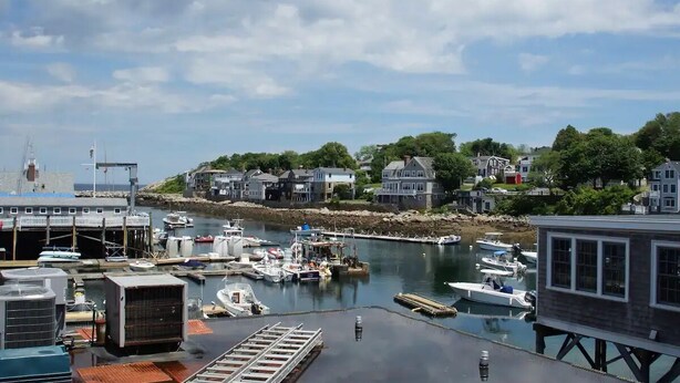 Un puerto con barcos amarrados, un muelle y casas a lo largo de la costa.