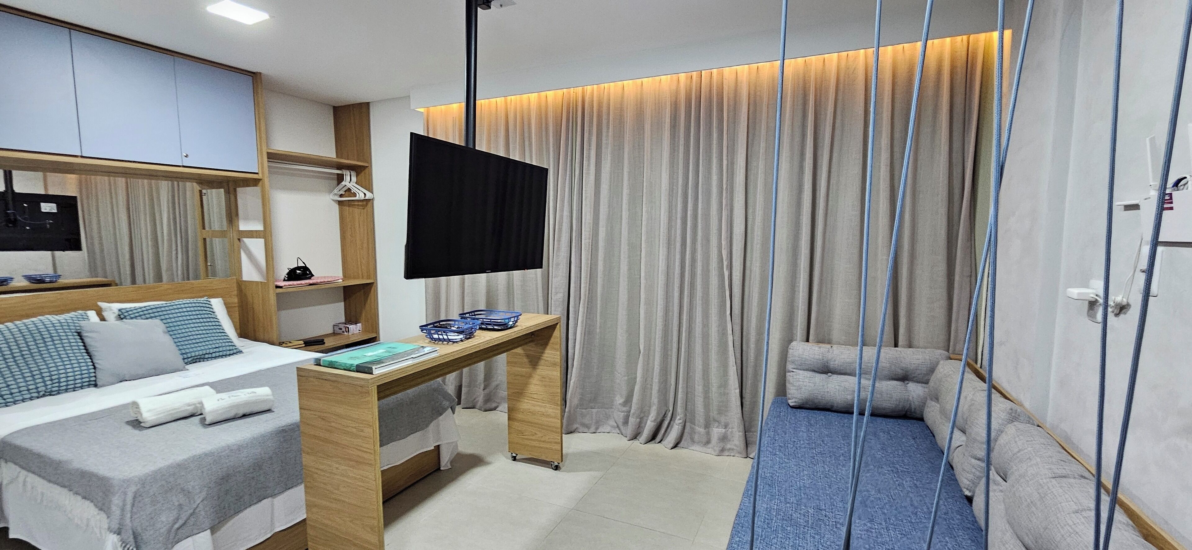 A modern hotel room with a bed, desk, TV, and seating area.