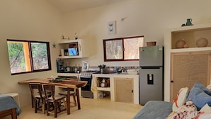 Una cocina compacta con zona de comedor, un refrigerador y una ventana con vista a zonas verdes.