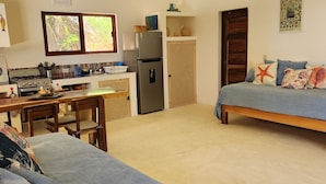 Un espacio habitable compacto con kitchenette, comedor y dos camas.