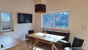 Un espace repas moderne avec une table en bois, des chaises noires et un luminaire suspendu.