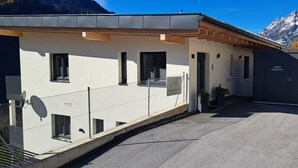 Un bâtiment moderne à la façade blanche, doté d’un portail noir, avec une chaîne de montagnes en arrière-plan.