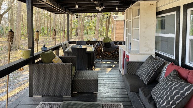 A covered outdoor seating area with wicker furniture, a sofa, and a dining table. - RAINBOW RANCH CABINS (Dunnellon)