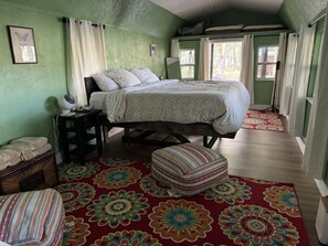 A bedroom with a bed, a bedside table, a lamp, a window, and a view of the outdoors. - RAINBOW RANCH CABINS (Dunnellon)