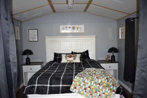 A bedroom with a bed, two bedside tables, a headboard, and a wall-mounted picture. - RAINBOW RANCH CABINS (Dunnellon)