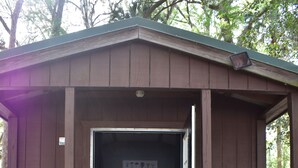 A small wooden cabin with a bed, a bench, and a mushroom decoration. - RAINBOW RANCH CABINS (Dunnellon)