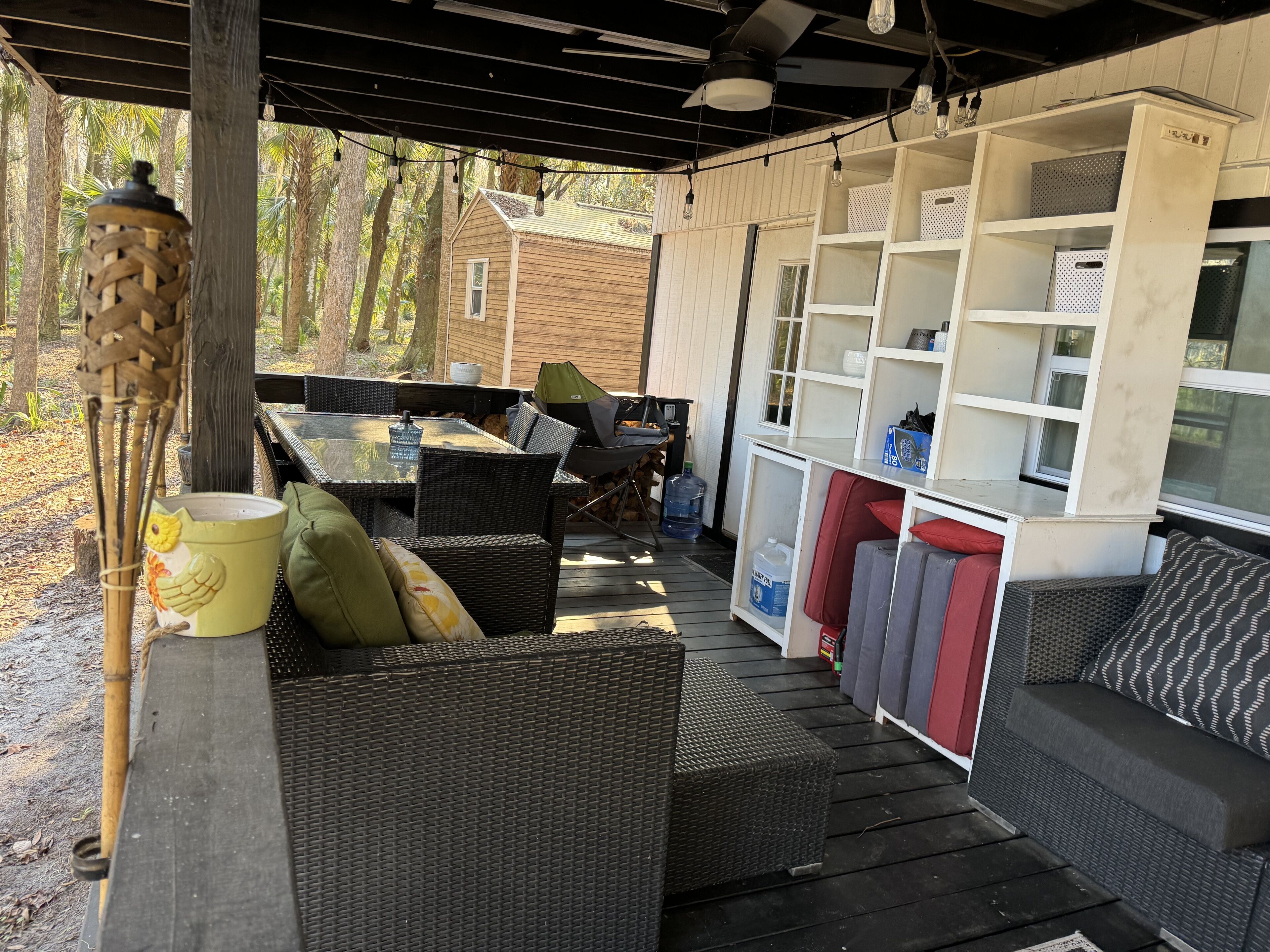An outdoor patio area with wicker furniture, a dining table, and a built-in storage unit.