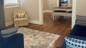 Una sala de estar con un sofá azul, un sillón a rayas y una alfombra estampada.