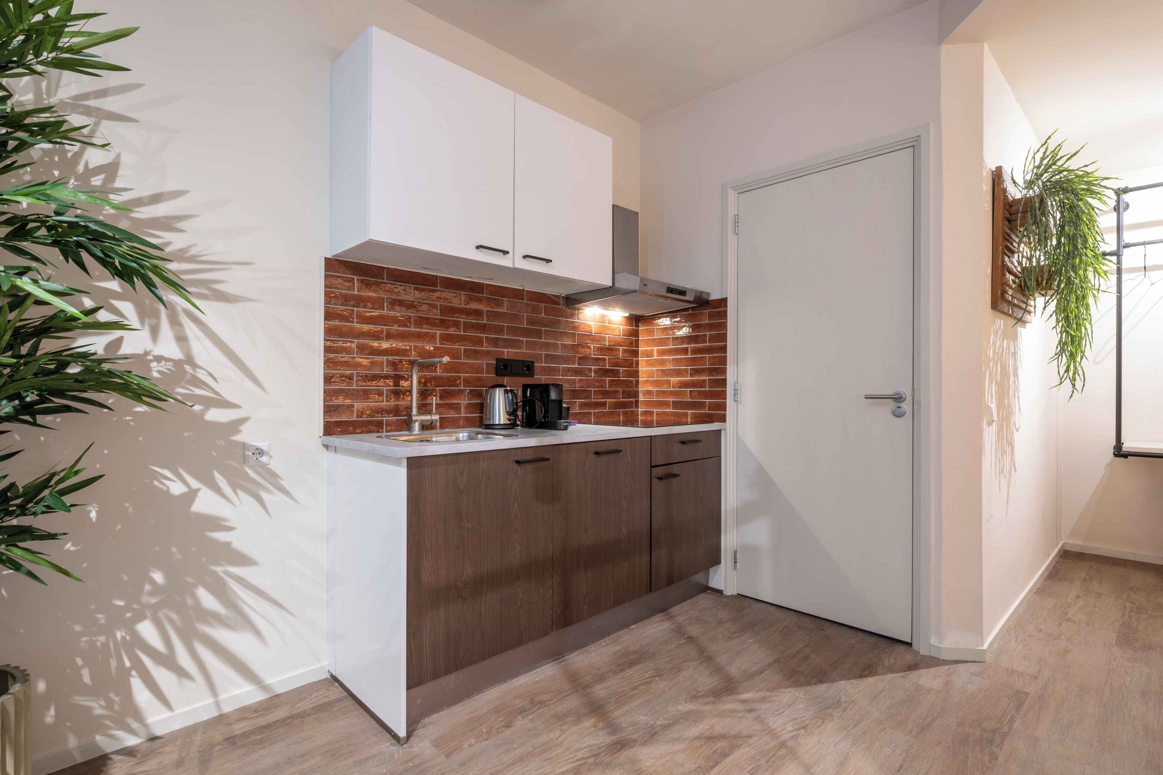 A kitchen with white cabinets, a brick backsplash, and a coffee maker.
