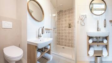 A modern bathroom with a toilet, a sink, a shower, and a mirror.