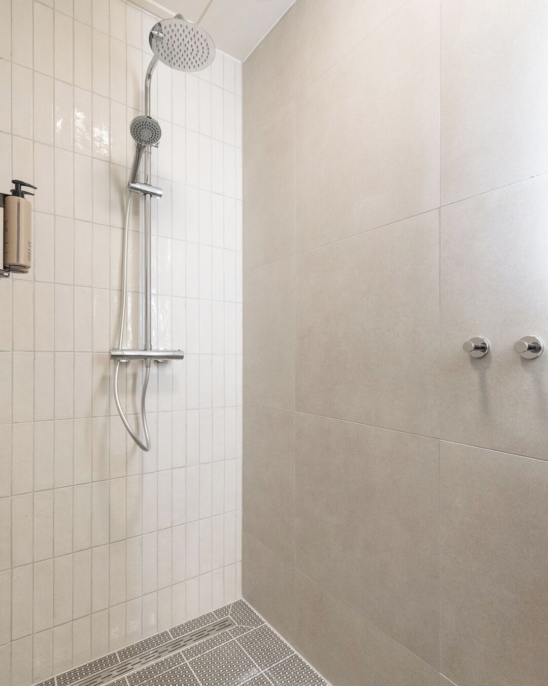 Une douche équipée d’un pommeau de douche à main et d’un robinet fixé au mur.