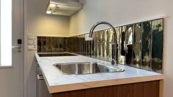 Een moderne keuken met een roestvrijstalen spoelbak, houten kastjes en een marmeren aanrecht.