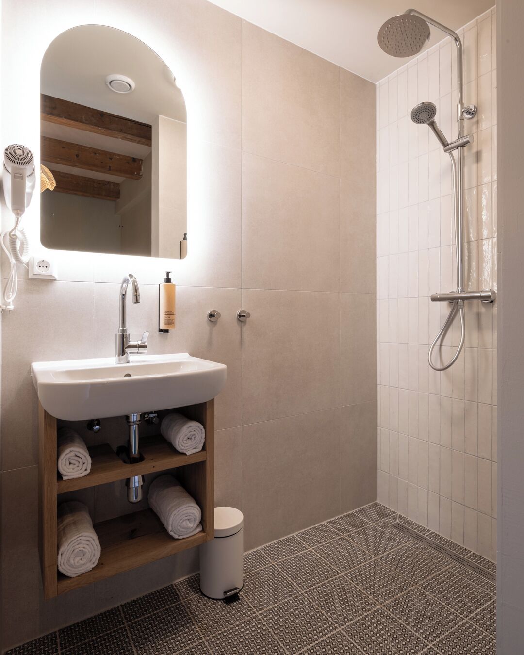 A modern bathroom with a white sink, a mirror, a shower, and a towel rack.