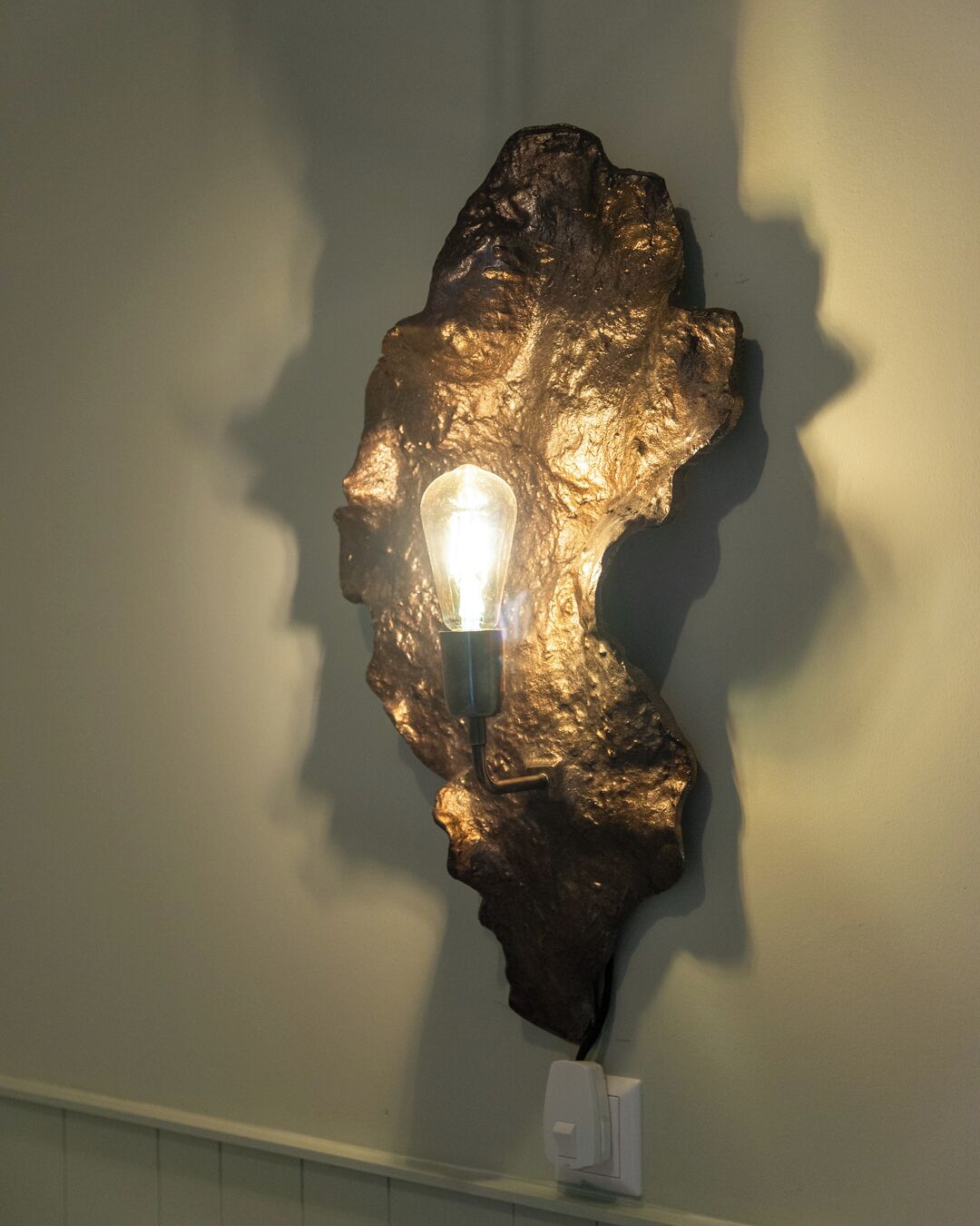 Une sculpture murale agrémentée d’un luminaire.