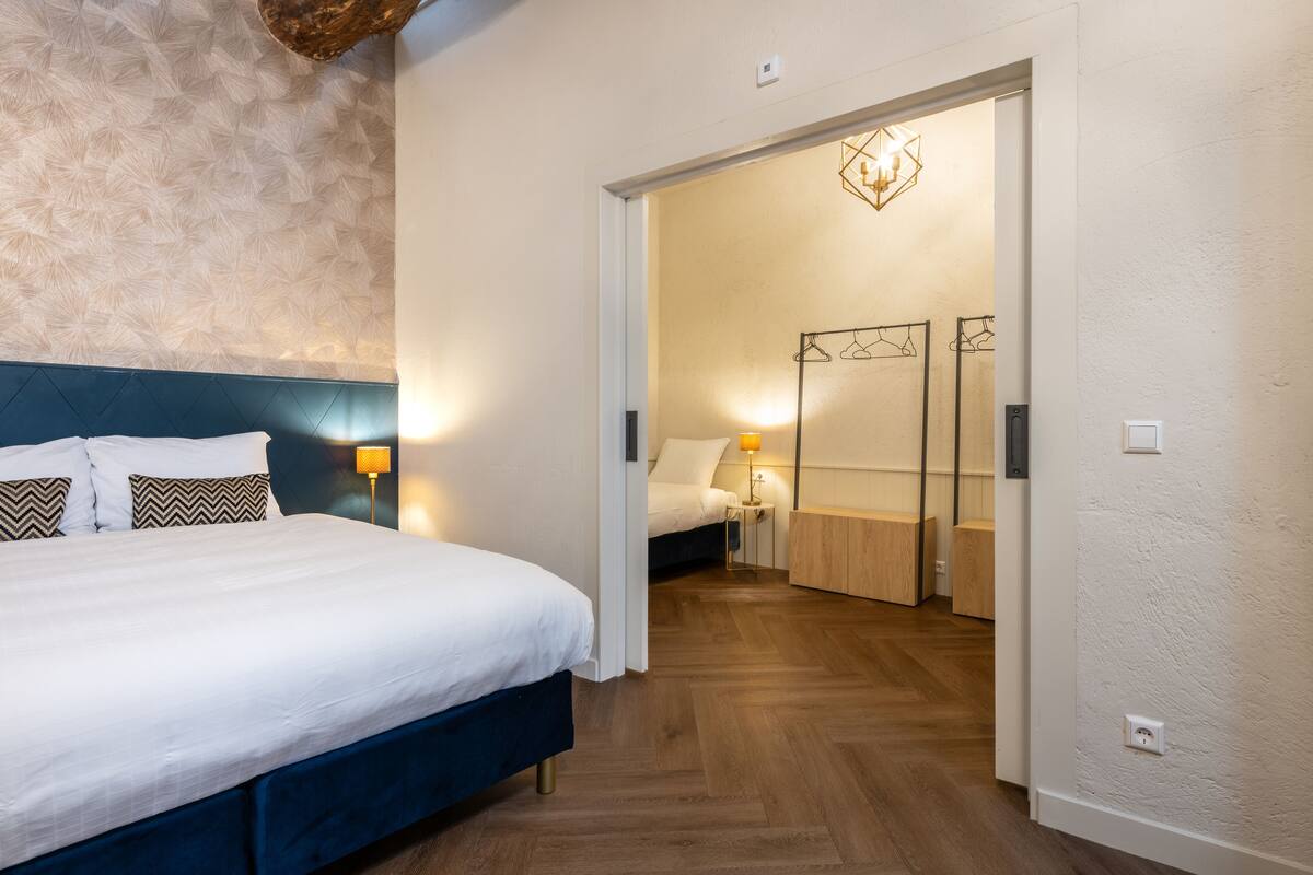 A hotel room with a large bed, a wardrobe, and a mirror.