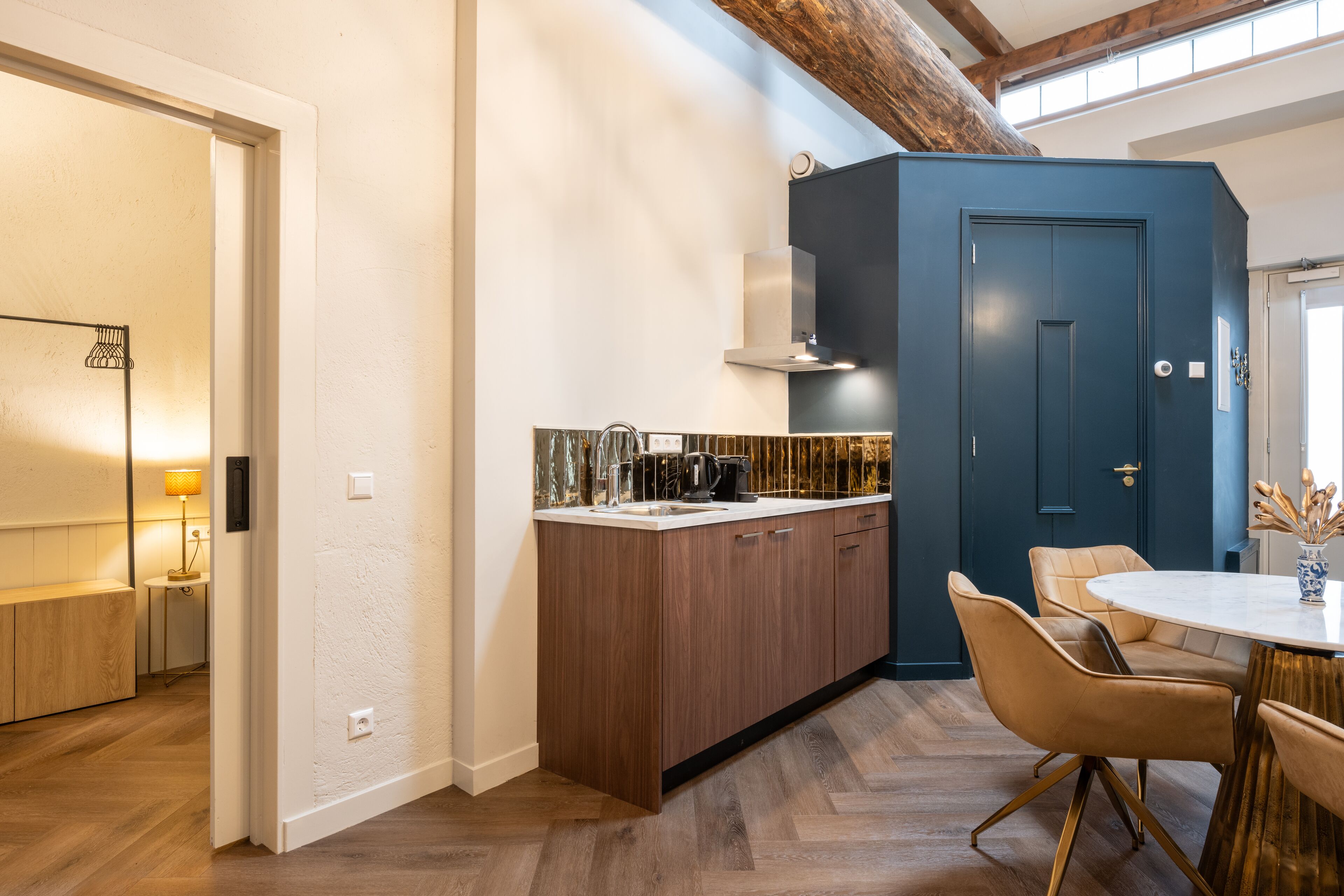 Una cocina moderna con armarios de madera, estufa integrada y una zona de comedor con una mesa redonda y sillas.