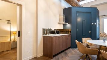 Una cocina moderna con armarios de madera, estufa integrada y una zona de comedor con una mesa redonda y sillas.