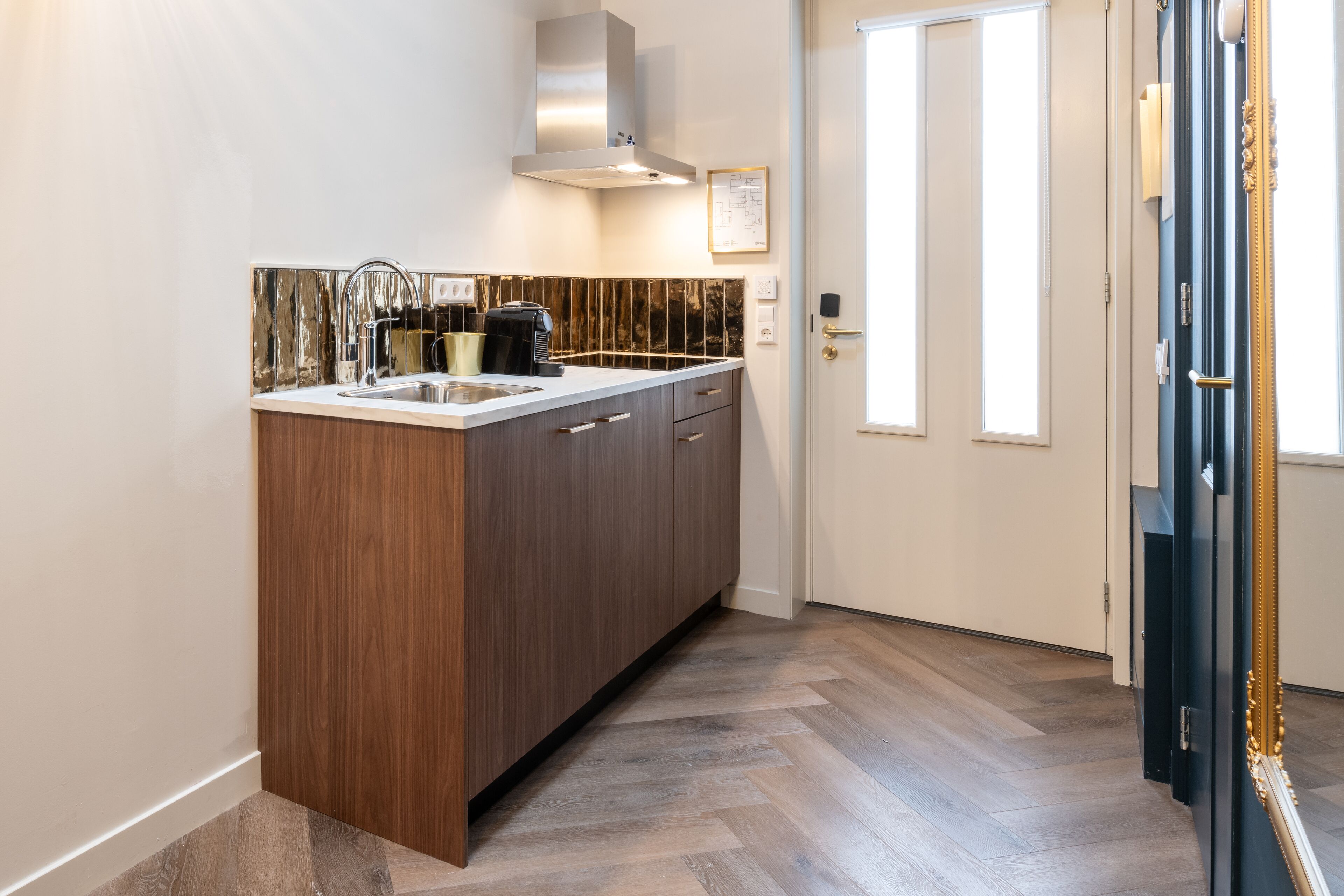 A modern kitchen with a built-in sink, wooden cabinets, and a herringbone-patterned floor.
