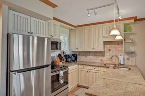 A kitchen with a stainless steel refrigerator, double oven, and a microwave. There are wooden cabinets and a granite countertop.