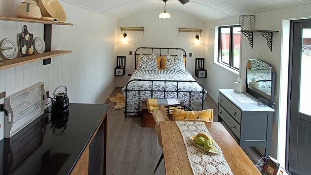 A modern bedroom with a bed, bedside tables, a desk, and a large window.