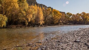 A river with a rocky shore and trees with autumn foliage.
