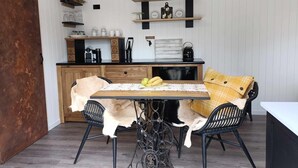 A rustic kitchen with a wooden table, chairs, and a black stove.