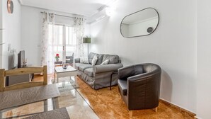 A modern living room with a grey sofa, a black leather chair, a wooden coffee table, and a TV. - Cozy apartment in Torrevieja with swimming pool (Torrevieja)