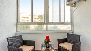 A room with two wicker chairs, a glass table, a bottle of wine, and two glasses. - Cozy apartment in Torrevieja with swimming pool (Torrevieja)