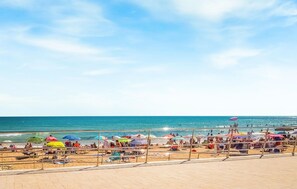 A beach with a clear sky, a sandy shore, and people enjoying the water.