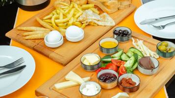 A table set with a variety of foods including bread, cheese, olives, and a cup of tea.