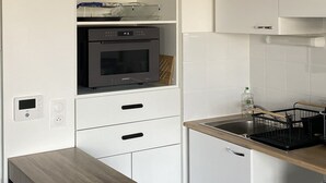 Una cocina moderna con armarios blancos, horno empotrado y encimera de madera.
