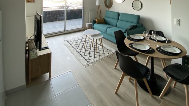Una sala moderna con comedor, sofá y televisor.