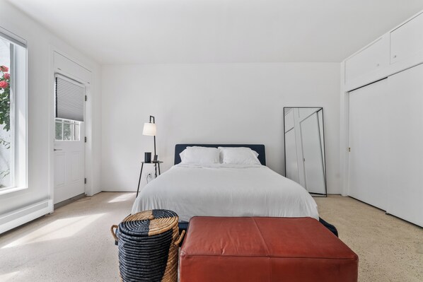 Un dormitorio con cama, mesita de noche, lámpara y un espejo grande.
