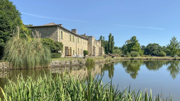 A stone building with a pond in front, surrounded by greenery. - Lake front home in Chiché with house sea view (Chiché)