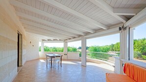 A covered patio with a table and chairs, a sofa, and a view of greenery. - Stunning home in Carovigno with WiFi (Carovigno)