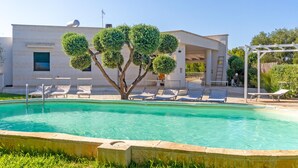 A swimming pool with lounge chairs, a pergola, and a building with a modern design. - Stunning home in Carovigno with WiFi (Carovigno)