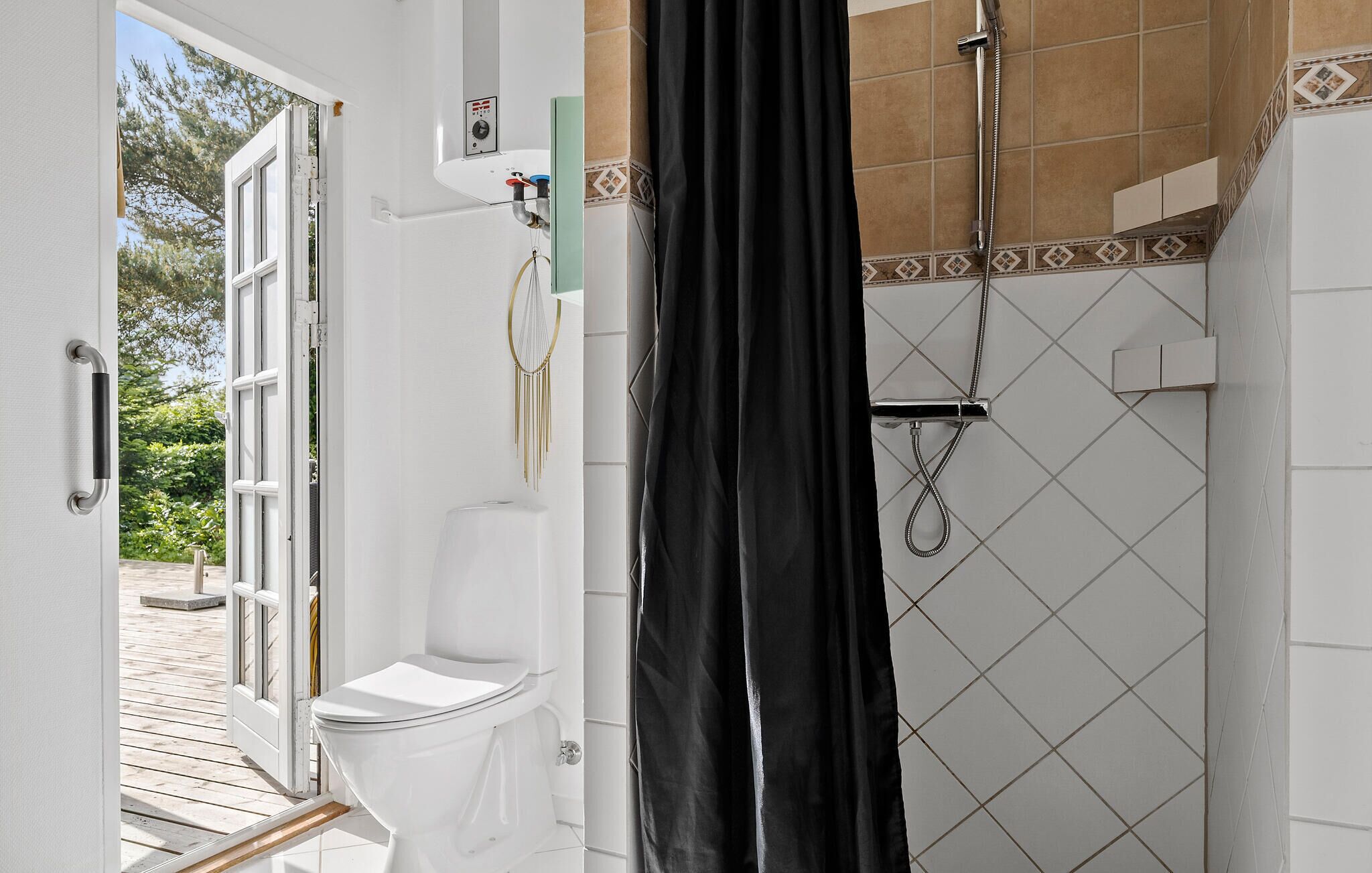 Un baño con inodoro, ducha con cortina y calentador de agua a la vista.