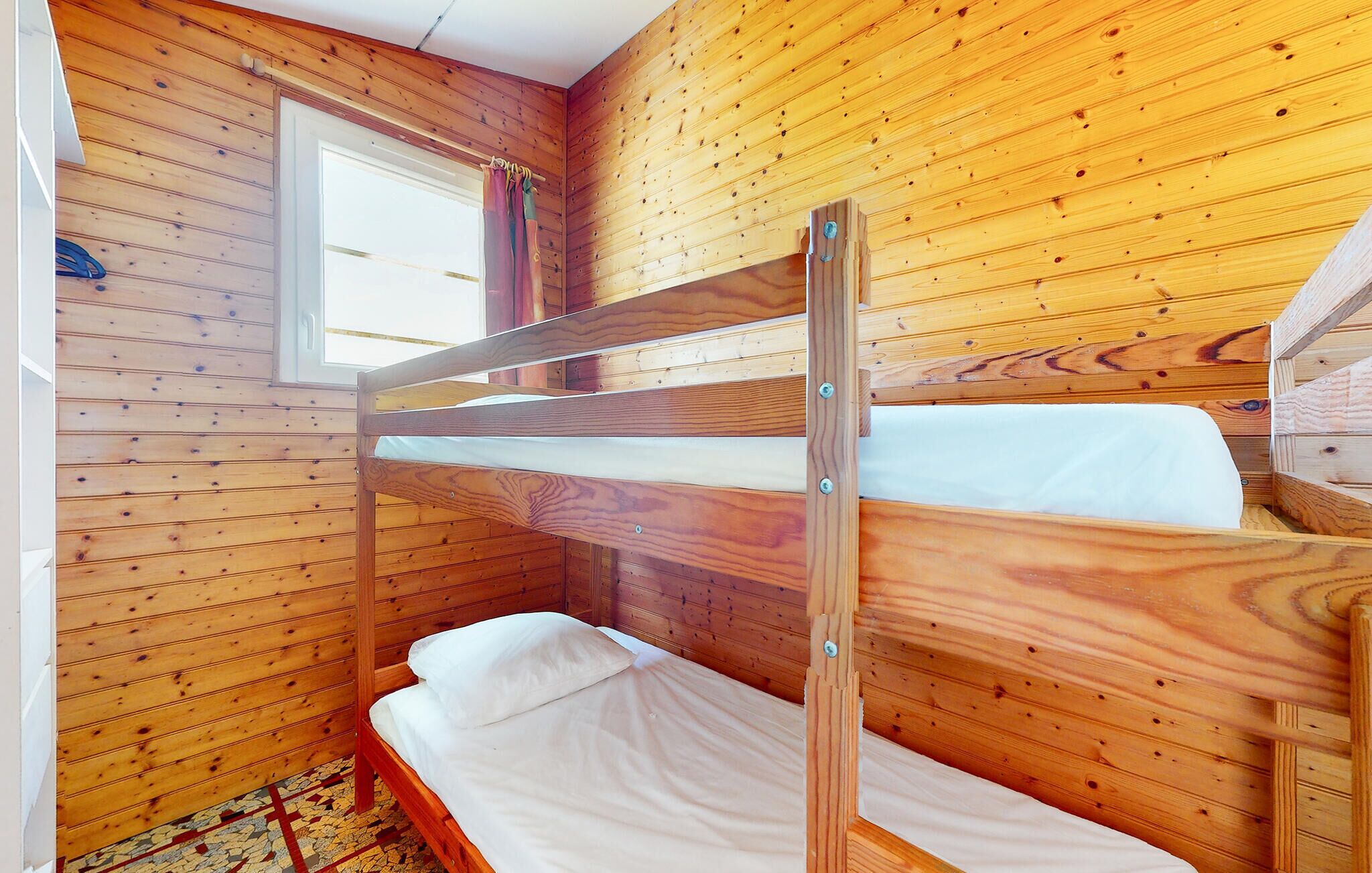 A bunk bed room with wooden walls and a window.