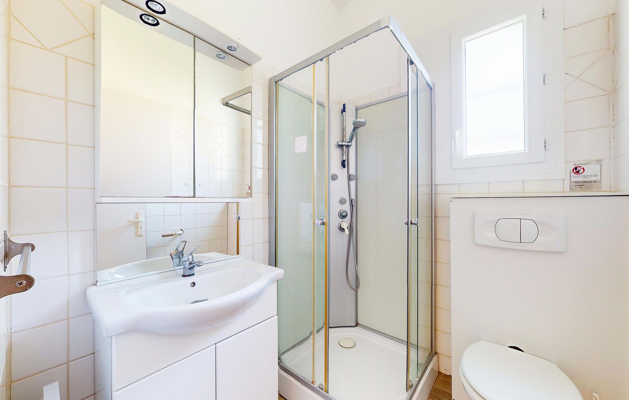 A modern bathroom with a glass-enclosed shower, a white sink, and a toilet.