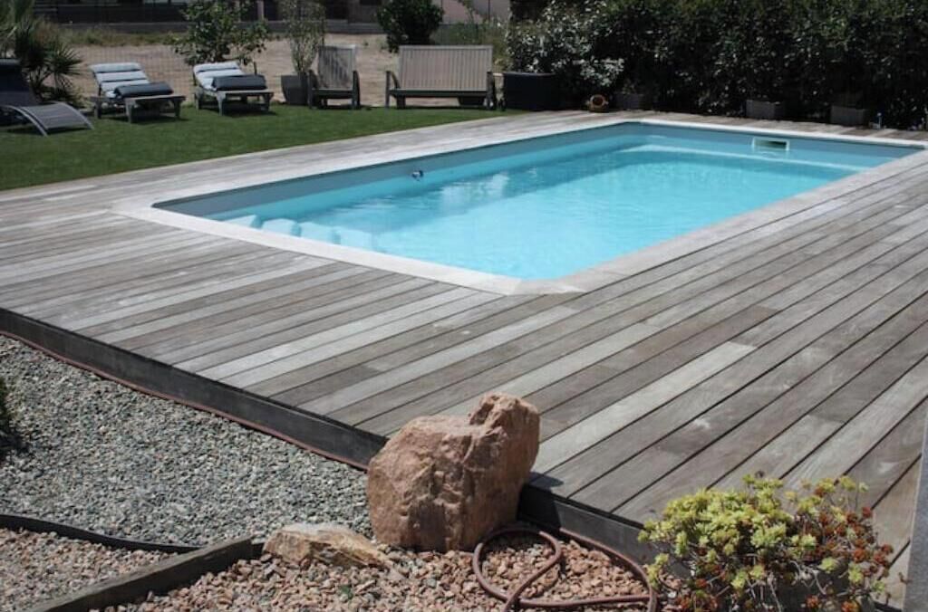 Ein rechteckiger Pool mit einer ihn umgebenden Holzterrasse.