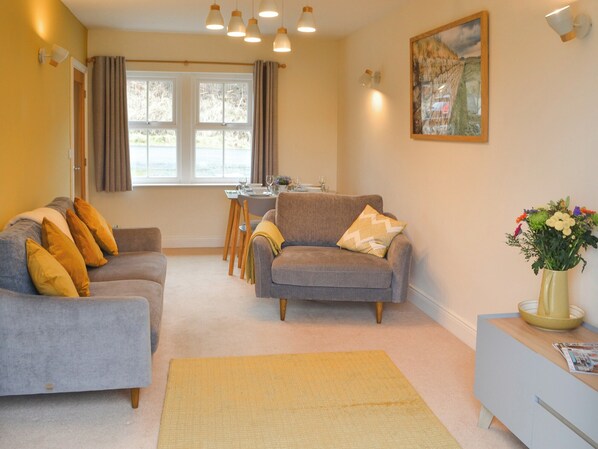 A living room with two sofas, a dining table, and a vase of flowers.