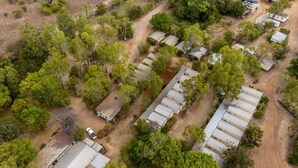 Vista aérea de un camping con varias cabañas tipo autocaravana, una piscina y abundante vegetación circundante.