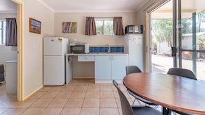 Una cocina compacta con refrigerador, microondas y pileta. Hay una mesa de comedor con sillas.