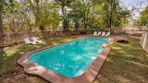 Una piscina rectangular con cubierta de madera y borde de ladrillo.