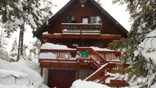 A wooden cabin with a balcony and stairs, surrounded by snow-covered trees. - 3 BR+loft, fam. rm., 2 bth, lg deck, close to major ski areas, trails, history. (Soda Springs)