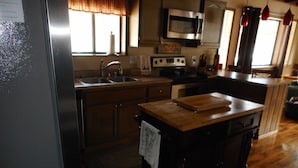 A kitchen with a wooden island, stainless steel appliances, and a window with curtains. - 3 BR+loft, fam. rm., 2 bth, lg deck, close to major ski areas, trails, history. (Soda Springs)