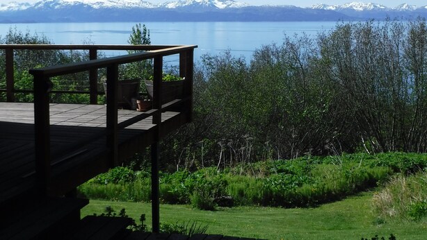 Una terraza de madera con vistas a un lago y montañas al fondo.