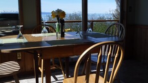 Un comedor con mesa, sillas y vista al mar.